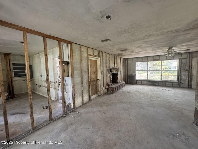unfurnished living room with visible vents, a ceiling fan, and a fireplace