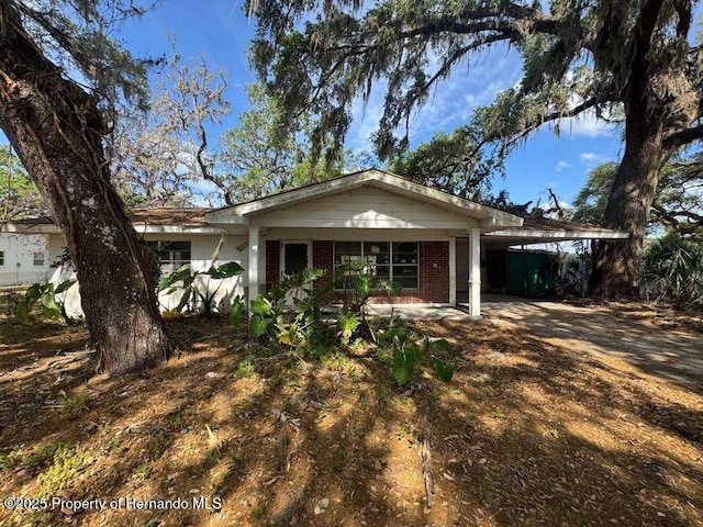 single story home featuring brick siding and a carport