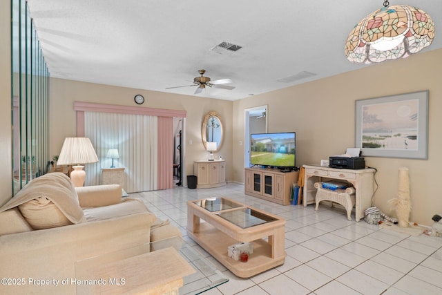 living area featuring ceiling fan, visible vents, baseboards, and tile patterned flooring