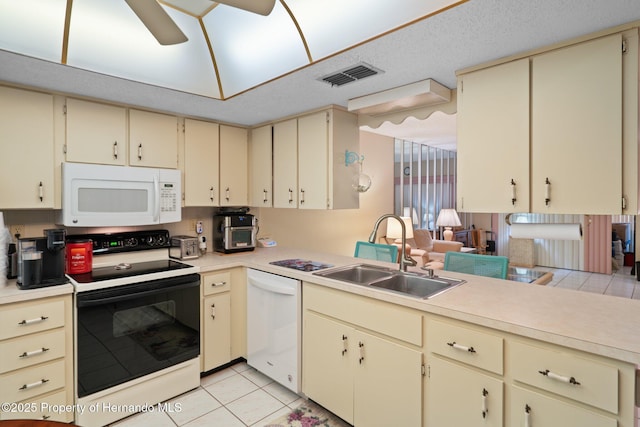kitchen with white appliances, a sink, cream cabinetry, and visible vents