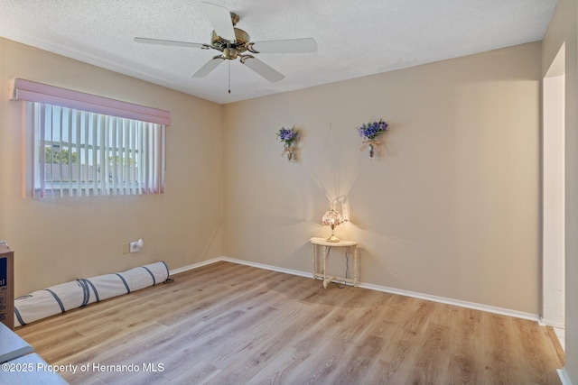 unfurnished room featuring baseboards, a ceiling fan, and wood finished floors