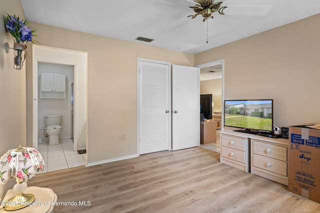 bedroom featuring ceiling fan, visible vents, a closet, light wood finished floors, and ensuite bath