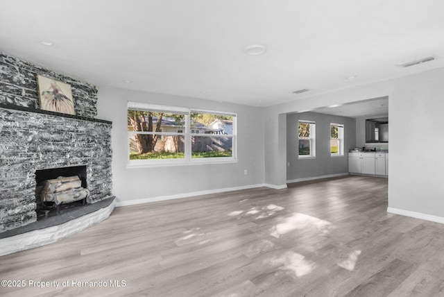 406 Zoller St, Brooksville, FL 34601 - unfurnished living room with a stone fireplace, baseboards, visible vents, and wood finished floors