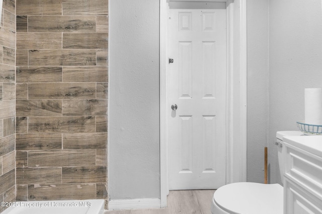 406 Zoller St, Brooksville, FL 34601 - full bath featuring vanity, a tile shower, toilet, a textured wall, and wood finished floors