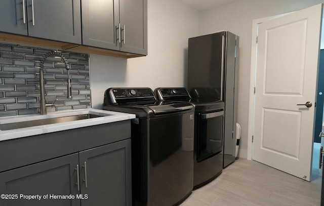 1156 Battersea Ave, Spring Hill, FL 34609 - laundry room with cabinet space, a sink, separate washer and dryer, and light wood-style floors
