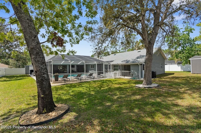 1156 Battersea Ave, Spring Hill, FL 34609 - back of property featuring a lanai, a fenced backyard, a storage unit, a lawn, and an outbuilding