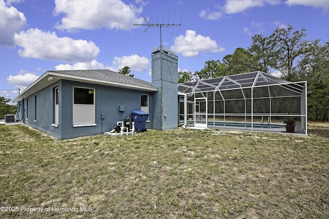 rear view of house featuring central AC unit, a lawn, a swimming pool, and glass enclosure