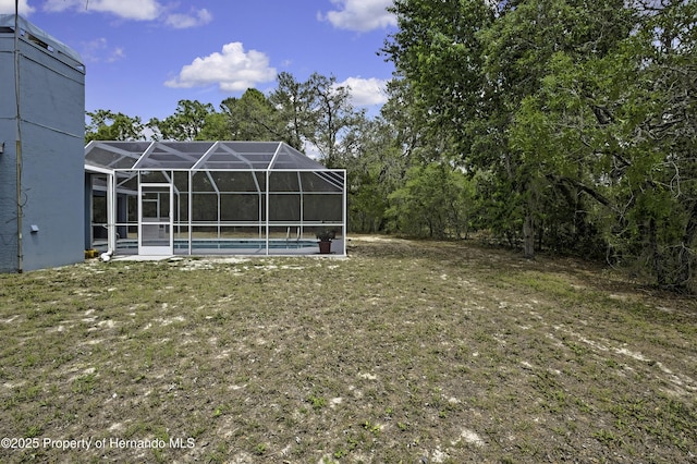 view of grassy yard featuring an outdoor pool and glass enclosure