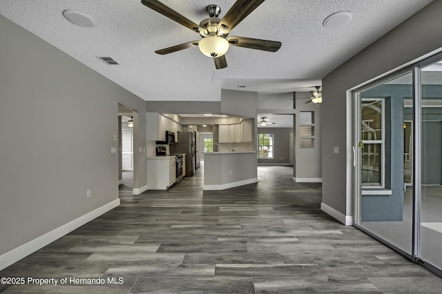 unfurnished living room featuring a ceiling fan, a textured ceiling, baseboards, and dark wood-style flooring