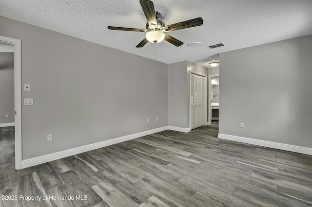 unfurnished room featuring ceiling fan, wood finished floors, baseboards, and a textured ceiling