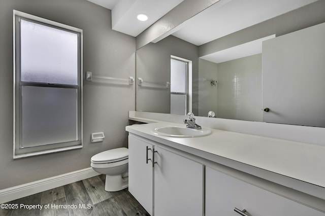 full bath with toilet, baseboards, wood finished floors, vanity, and a shower