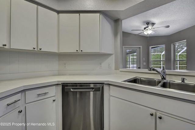 kitchen featuring stainless steel dishwasher, a sink, a ceiling fan, light countertops, and a textured ceiling
