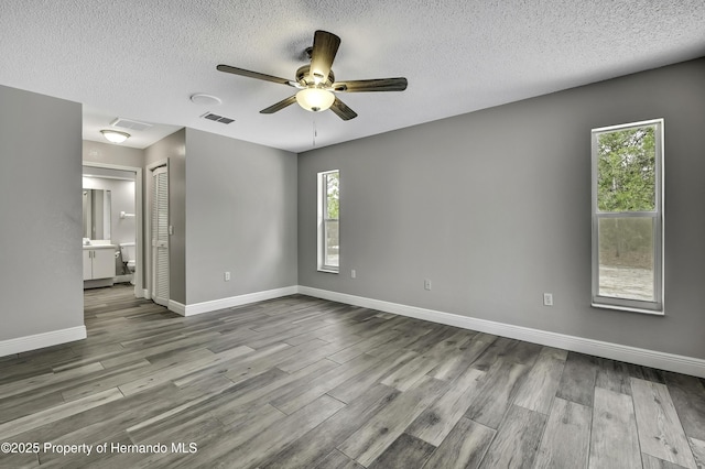 unfurnished bedroom featuring wood finished floors, a closet, a textured ceiling, baseboards, and ceiling fan