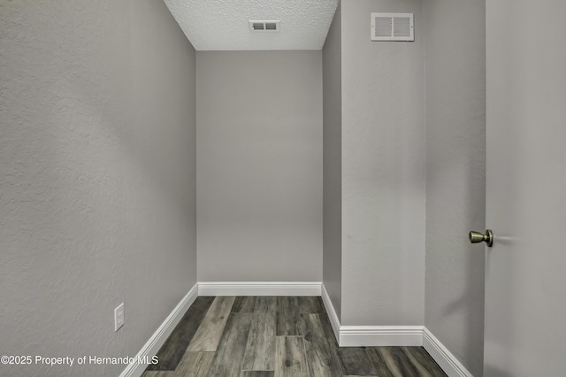 interior space featuring a textured ceiling, dark wood-type flooring, and baseboards