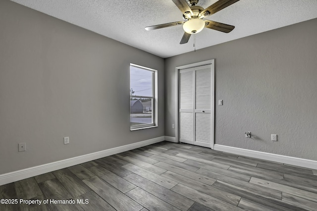 unfurnished room featuring ceiling fan, a textured ceiling, wood finished floors, and baseboards