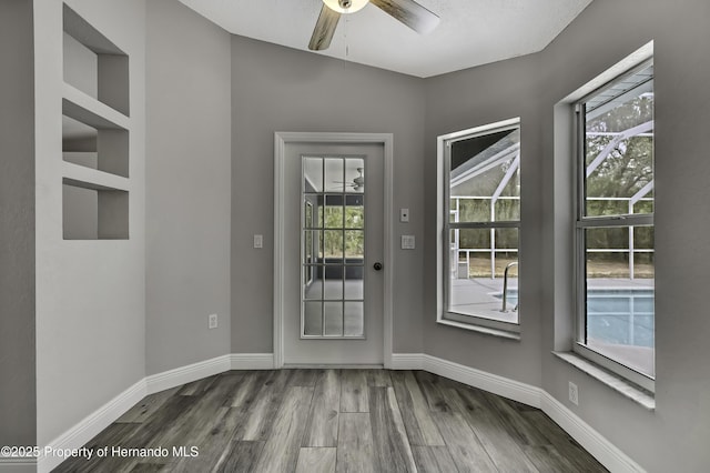entryway with wood finished floors, ceiling fan, and baseboards