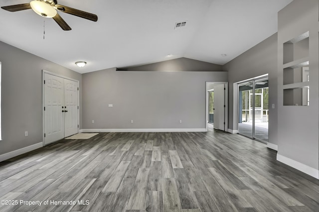 unfurnished living room with ceiling fan, lofted ceiling, wood finished floors, and baseboards