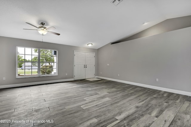 unfurnished living room with vaulted ceiling, wood finished floors, a ceiling fan, and baseboards