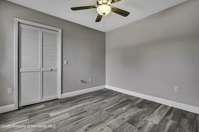 unfurnished room featuring wood finished floors, a ceiling fan, baseboards, and a textured ceiling