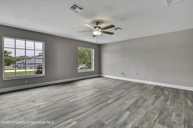 unfurnished room featuring wood finished floors, a ceiling fan, a textured ceiling, and baseboards