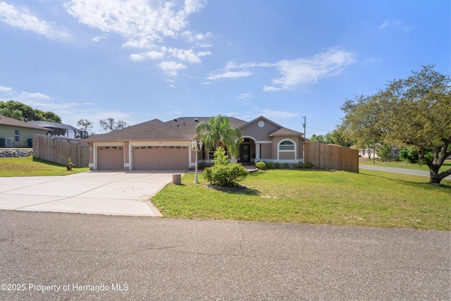 view of front of house featuring fence, an attached garage, stucco siding, a front lawn, and driveway