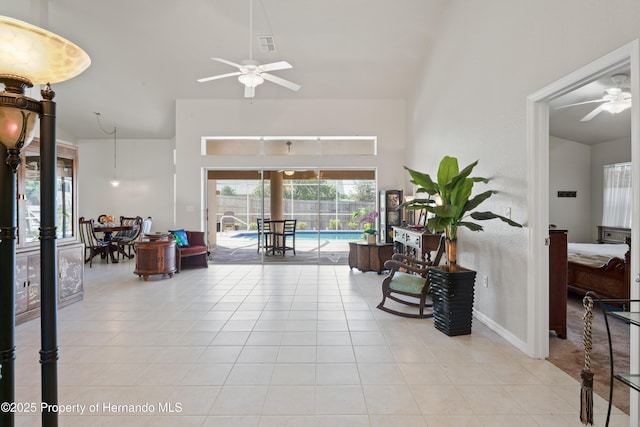 interior space featuring light tile patterned floors, visible vents, a high ceiling, and a ceiling fan
