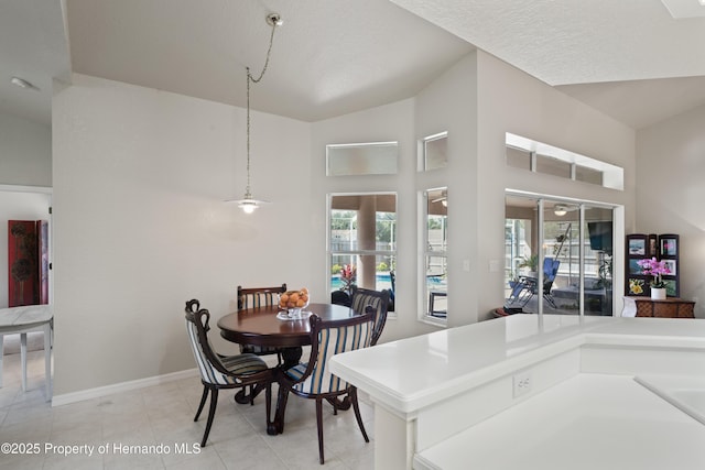 dining room featuring baseboards, high vaulted ceiling, a healthy amount of sunlight, and light tile patterned floors