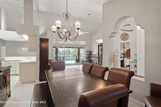 dining area with ceiling fan with notable chandelier, visible vents, high vaulted ceiling, and light tile patterned floors