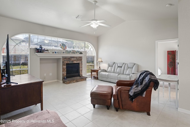 living room with vaulted ceiling, light tile patterned floors, visible vents, a stone fireplace, and ceiling fan