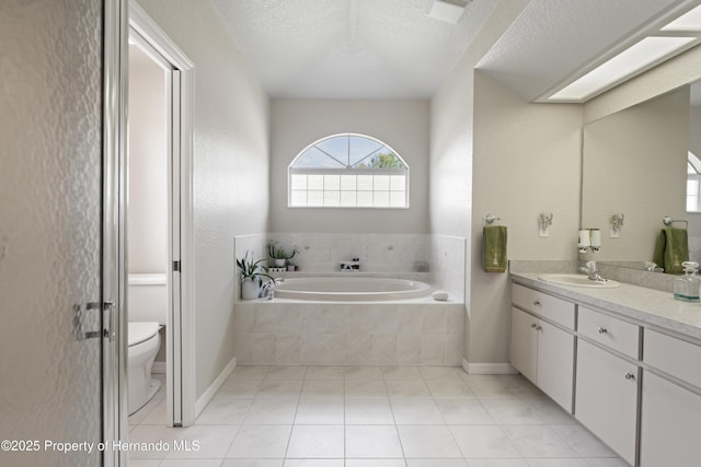 full bathroom with vanity, toilet, a textured ceiling, tile patterned floors, and a garden tub