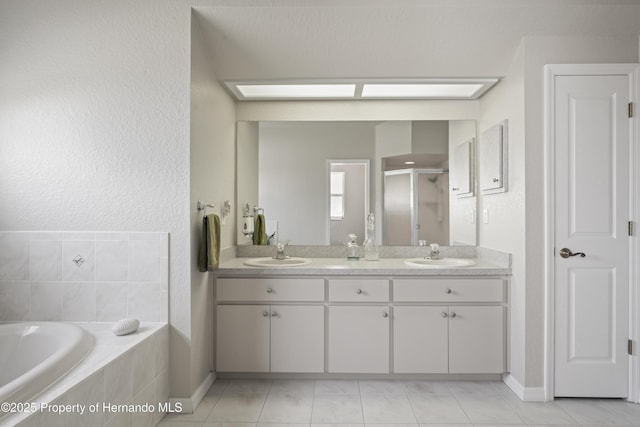 bathroom featuring a stall shower, double vanity, a bath, and a sink