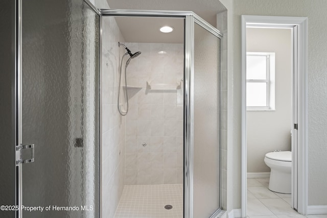 full bath featuring toilet, tile patterned floors, baseboards, and a shower stall