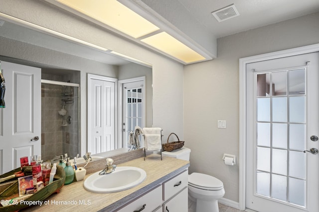 bathroom featuring a stall shower, toilet, vanity, baseboards, and visible vents
