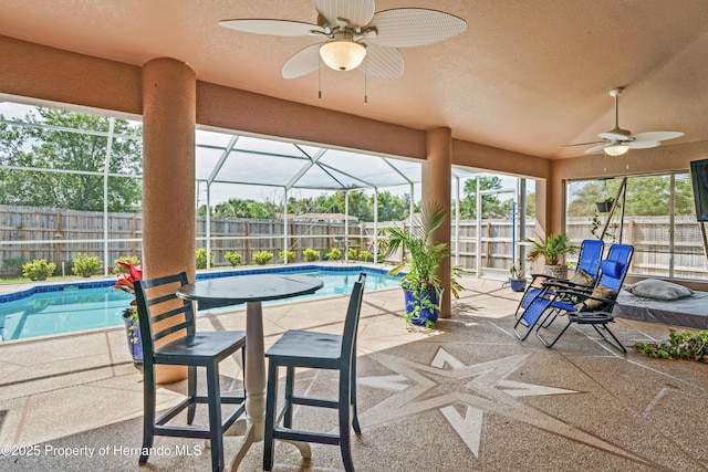 view of patio featuring a ceiling fan, a fenced backyard, a fenced in pool, and glass enclosure