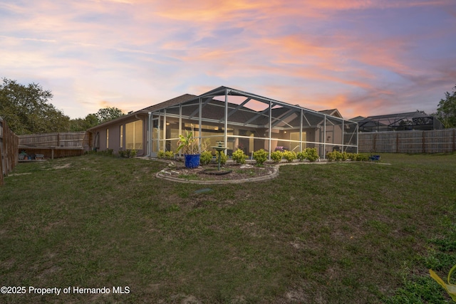 rear view of house featuring a fenced backyard, a lanai, and a yard