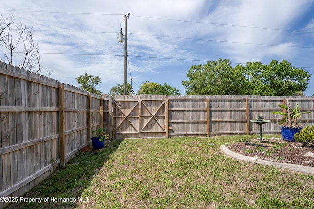 view of yard with a fenced backyard and a gate