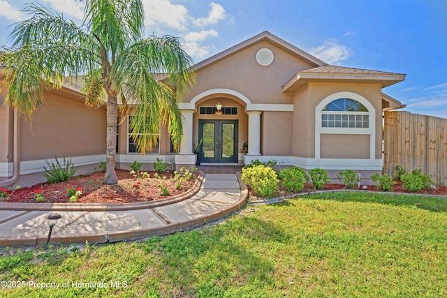 view of front of property featuring french doors, a front yard, stucco siding, and fence