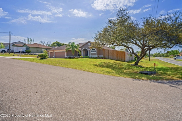 view of front of home with fence, driveway, a front yard, and a garage