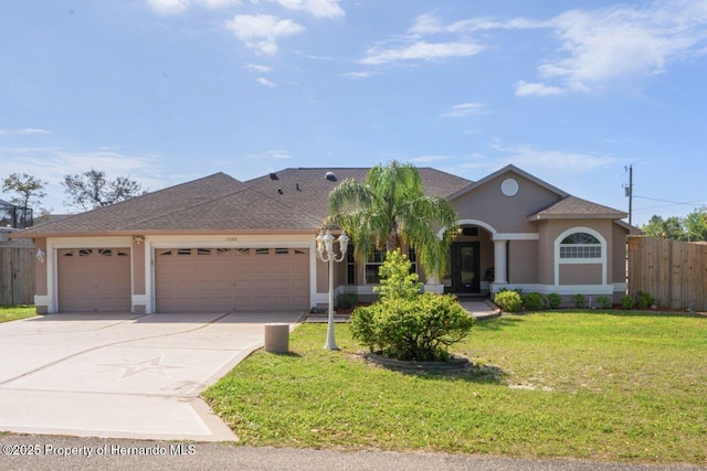 view of front of property featuring driveway, a front yard, stucco siding, fence, and an attached garage