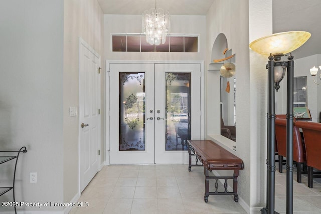 tiled foyer featuring baseboards, french doors, and a notable chandelier