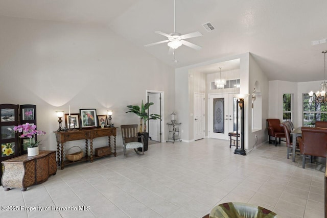 interior space featuring light tile patterned floors, high vaulted ceiling, ceiling fan with notable chandelier, and visible vents