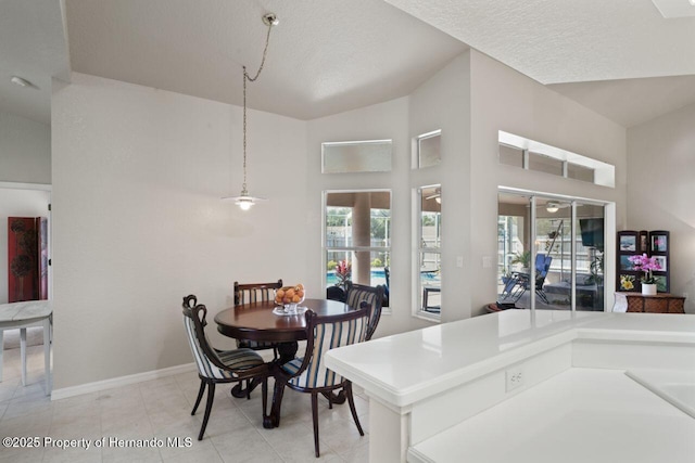 dining space with a wealth of natural light, high vaulted ceiling, baseboards, and light tile patterned floors