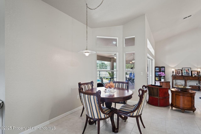 dining space with light tile patterned flooring, baseboards, visible vents, and high vaulted ceiling