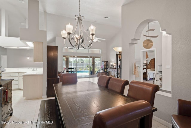 dining space with a notable chandelier, high vaulted ceiling, light tile patterned floors, visible vents, and a textured wall