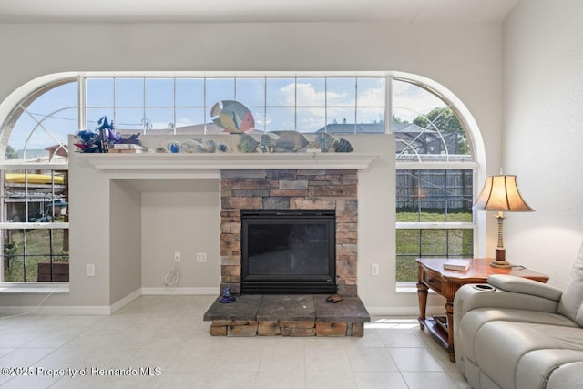 living area with baseboards, tile patterned floors, and a stone fireplace