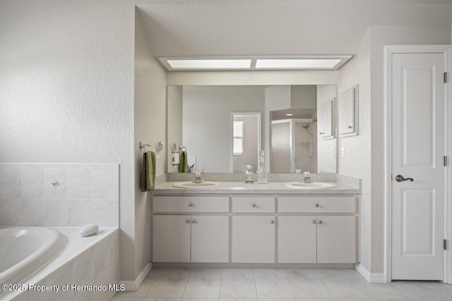 bathroom featuring a garden tub, double vanity, a sink, and a stall shower