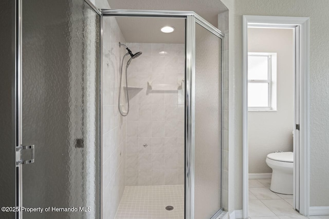 full bath with tile patterned floors, toilet, a stall shower, and baseboards