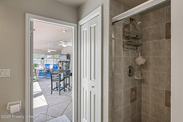 full bath with a shower stall, a textured wall, and a ceiling fan