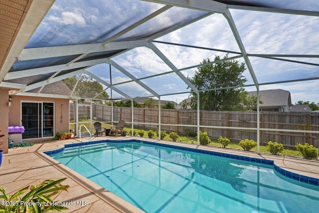view of pool with a fenced backyard, glass enclosure, a patio area, and a fenced in pool