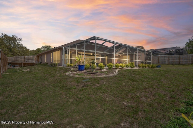 rear view of property featuring a fenced backyard, glass enclosure, and a yard